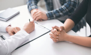 Medical consultation. Doctor writing prescription and treatment plan to couple of patients at clinic